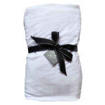 A white fitted cot sheet with a black ribbon tie, displayed against a plain background.