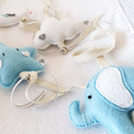 A set of four handcrafted dingle dangle toys in a blues and whites: a moon, star, cloud, and ellie. Made from soft felt with ribbons, designed for infant sensory development.