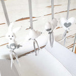 A set of four handcrafted dingle dangle toys in grey and white them: a bunny, heart, lamb, and cloud. Made from soft felt with ribbons, designed for infant sensory development.