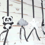 A set of four handcrafted dingle dangle toys in black and white them: a panda, feather, star, and cloud. Made from soft felt with ribbons, designed for infant sensory development.