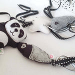 A set of four handcrafted dingle dangle toys in black and white them: a panda, feather, star, and cloud. Made from soft felt with ribbons, designed for infant sensory development.