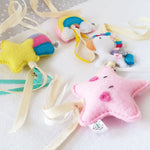 A set of four handcrafted dingle dangle toys in fantasy unicorn theme in bright colours: a unicorn, shooting star, star, and rainbow. Made from soft felt with ribbons, designed for infant sensory development.
