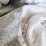 Close up of a grey baby change mat cover with a white towelling centre showing off the melange knit of the fabric