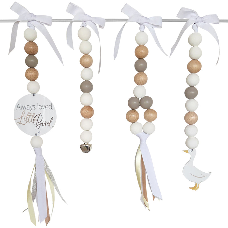 Decorative baby mobile with beads, ribbons, and a goose charm on a white background