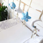 A set of four handcrafted dingle dangle toys in a blues and whites: a moon, star, cloud, and ellie. Made from soft felt with ribbons, designed for infant sensory development.
