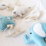 A set of four handcrafted dingle dangle toys in a blues and whites: a moon, star, cloud, and ellie. Made from soft felt with ribbons, designed for infant sensory development.
