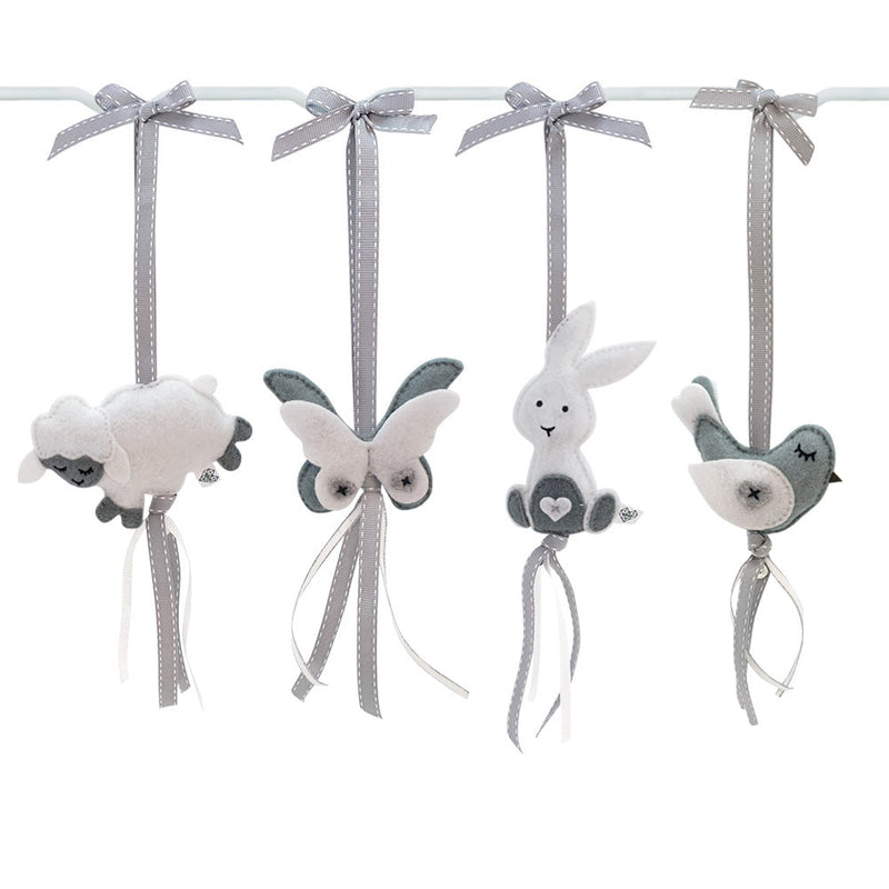 A set of four handcrafted dingle dangle toys in a meadow animal theme in grey and whit: a bunny, bird, lamb, and butterfly. Made from soft felt with ribbons, designed for infant sensory development.