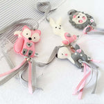 A set of four handcrafted dingle dangle toys in woodland animal shapes, made from soft felt with ribbons, designed for infant sensory development.